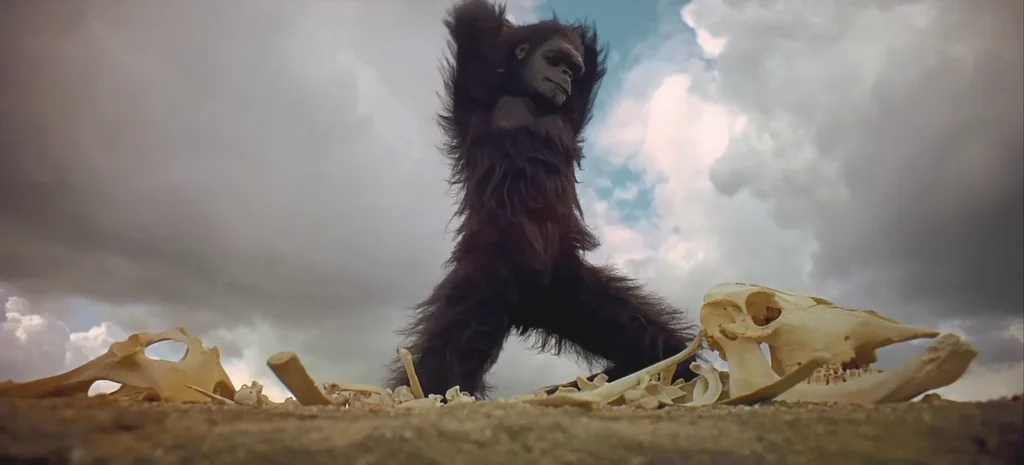 Figura simiesca erguida entre huesos bajo cielo dramático, evocando evolución y ritual