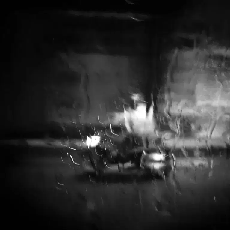 Moto bajo la lluvia vista a través de cristal mojado en Hô Chi Minh.