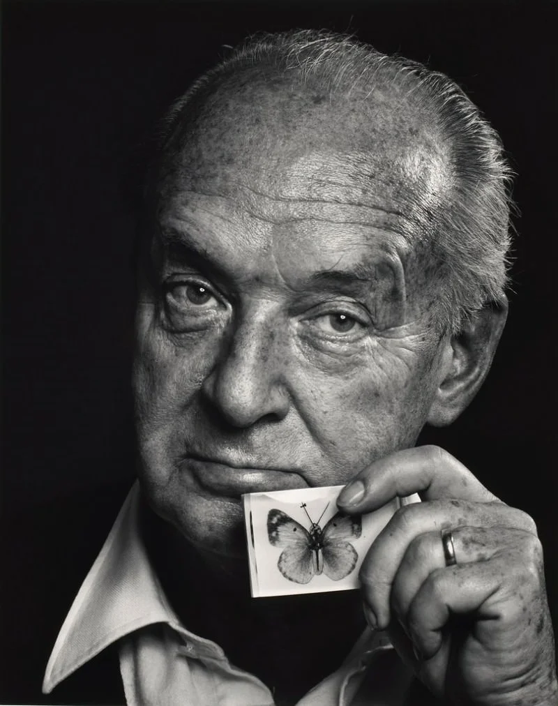 Retrato en blanco y negro de Vladimir Nabokov sosteniendo una tarjeta con una mariposa, símbolo de su pasión por la lepidopterología.