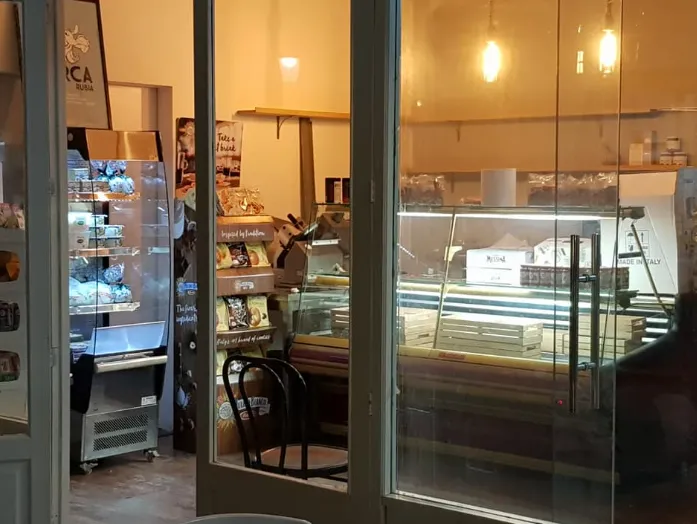 Interior de La Búfala de Alaró visto desde la entrada, con vitrinas iluminadas de panadería y pastelería artesanal.