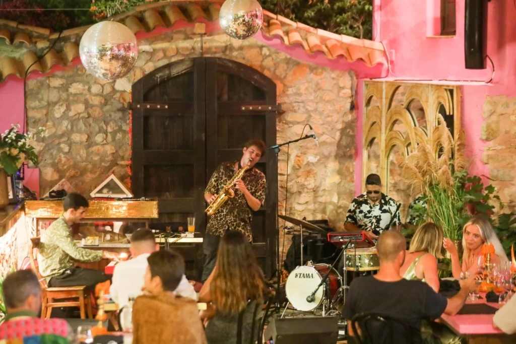 Banda de jazz tocando en un local con público cenando y decoración cálida.
