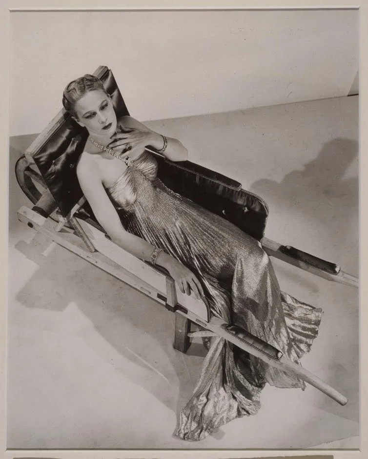 Mujer con vestido metálico reclinada sobre trineo en fotografía surrealista estilo Man Ray