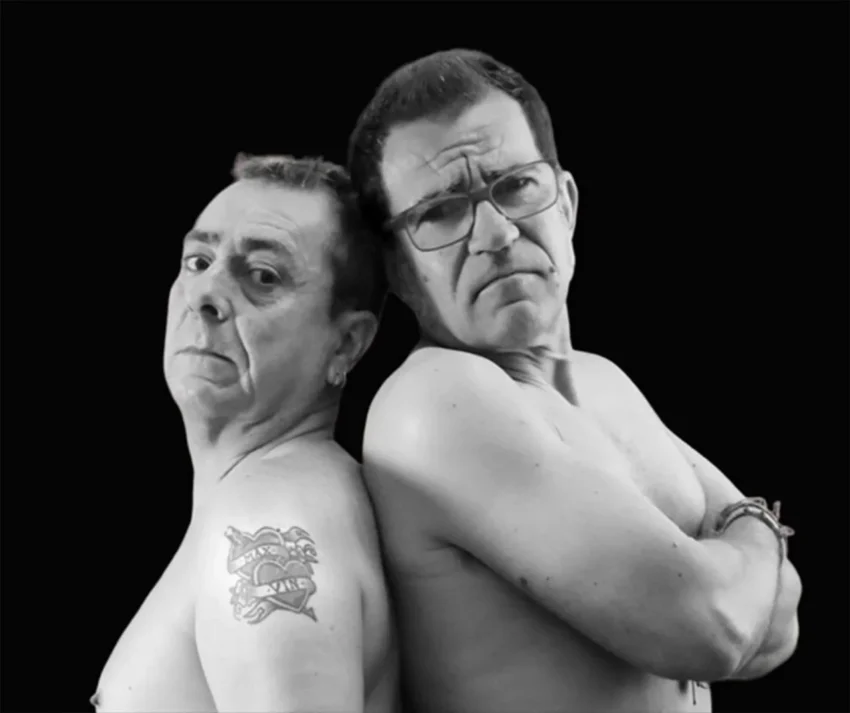 Carlos Penas y Miguel Monegal sin camiseta, espalda con espalda, en retrato en blanco y negro con fondo negro.