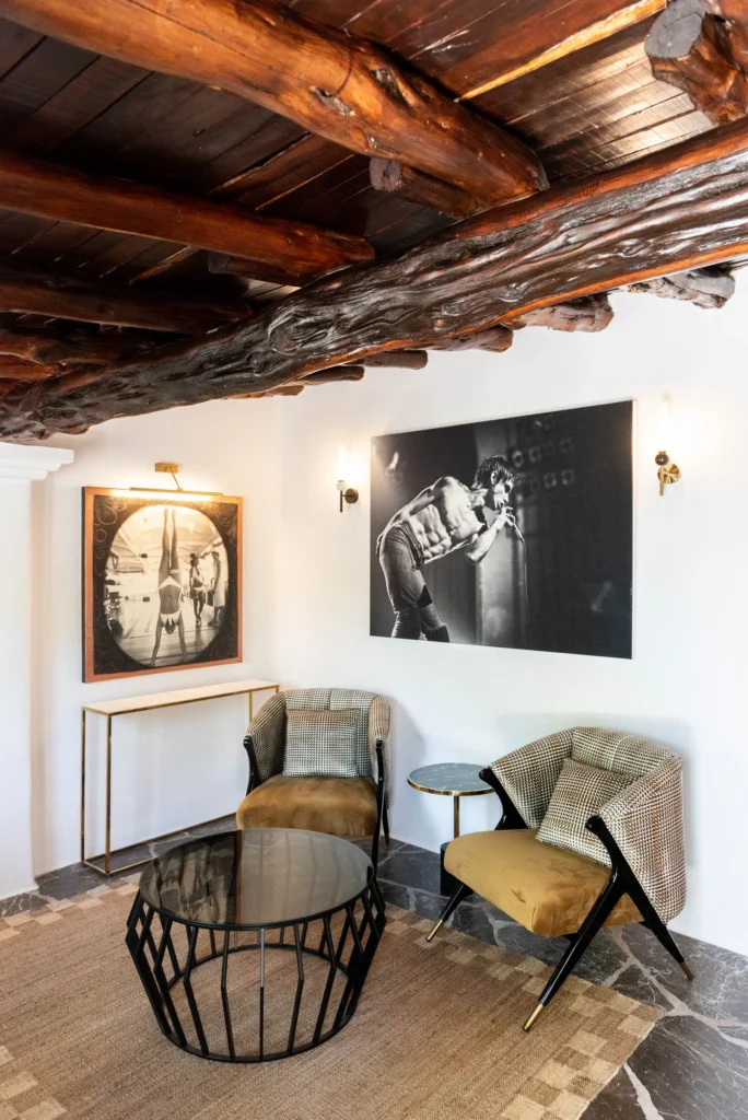 Rincón interior de Pikes Ibiza con fotografías en blanco y negro, butacas de diseño y techo de vigas de madera.