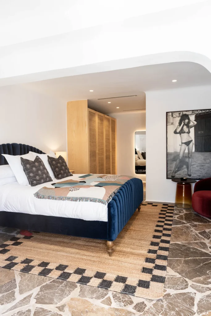 Habitación de Pikes Ibiza con cama tapizada en azul, fotografía en blanco y negro y decoración contemporánea.