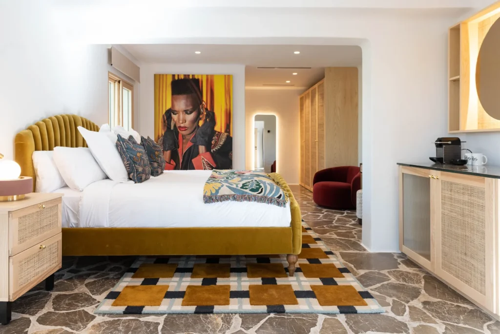 Habitación de Pikes Ibiza con cama mostaza, retrato artístico y detalles de diseño contemporáneo.