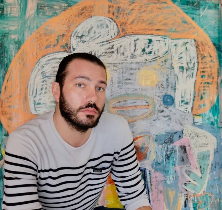Adam Handler frente a una pintura abstracta vibrante de su universo artístico.