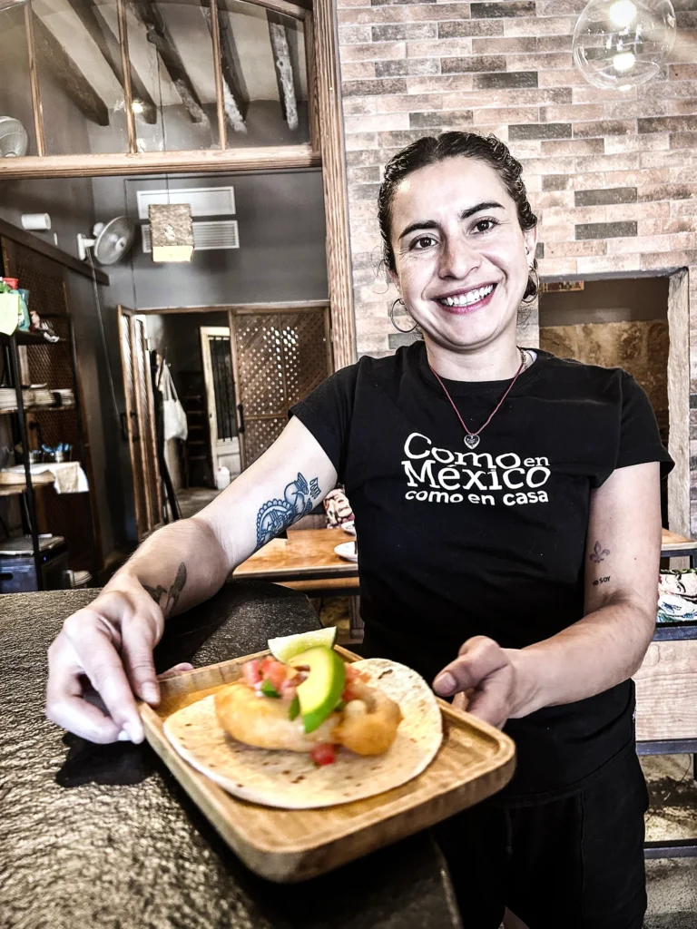 “Como en México como en casa” presentando taco sobre bandeja de madera en restaurante