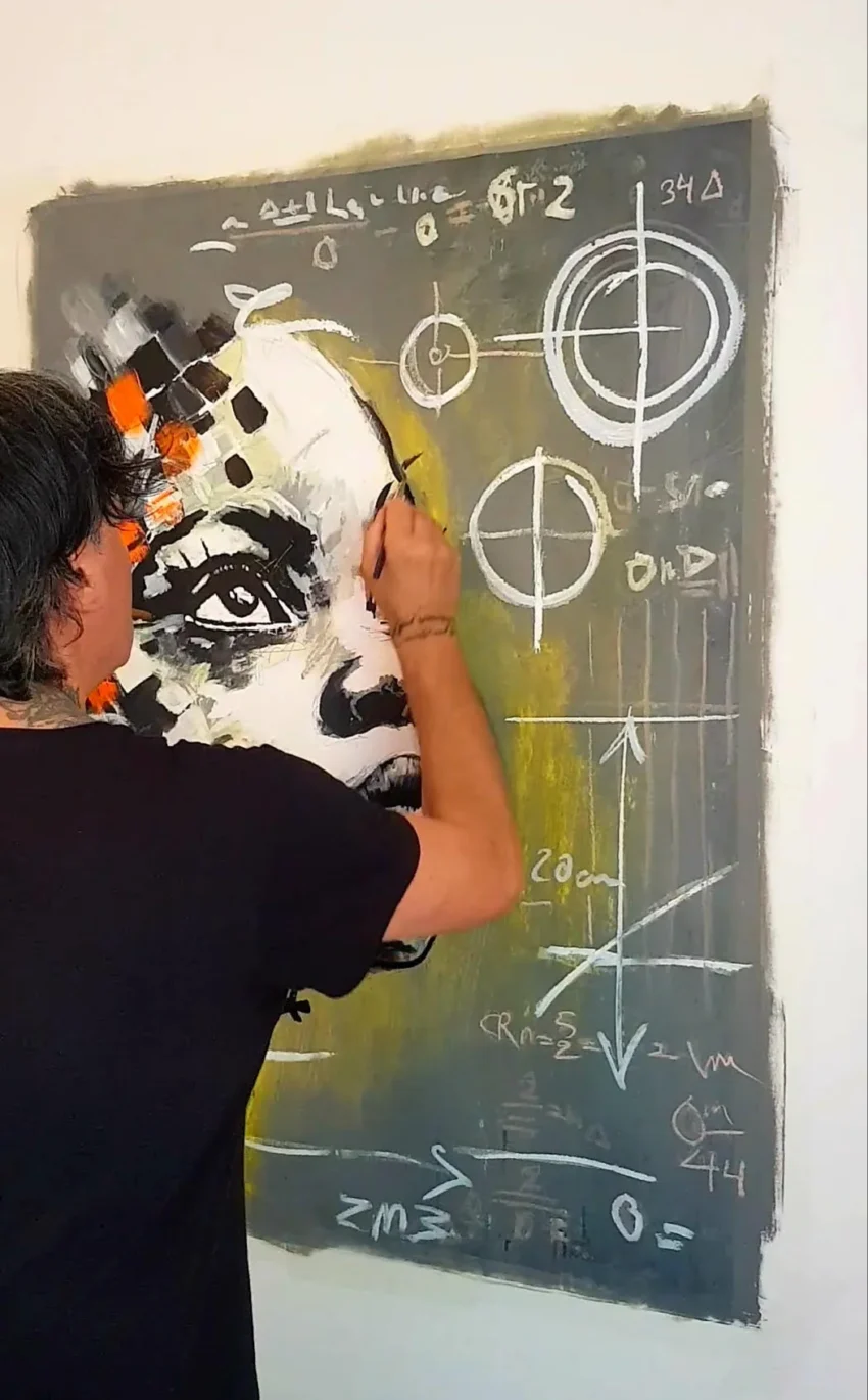 Franck Sastre pintando mural con rostro estilizado y símbolos matemáticos y científicos en fondo oscuro