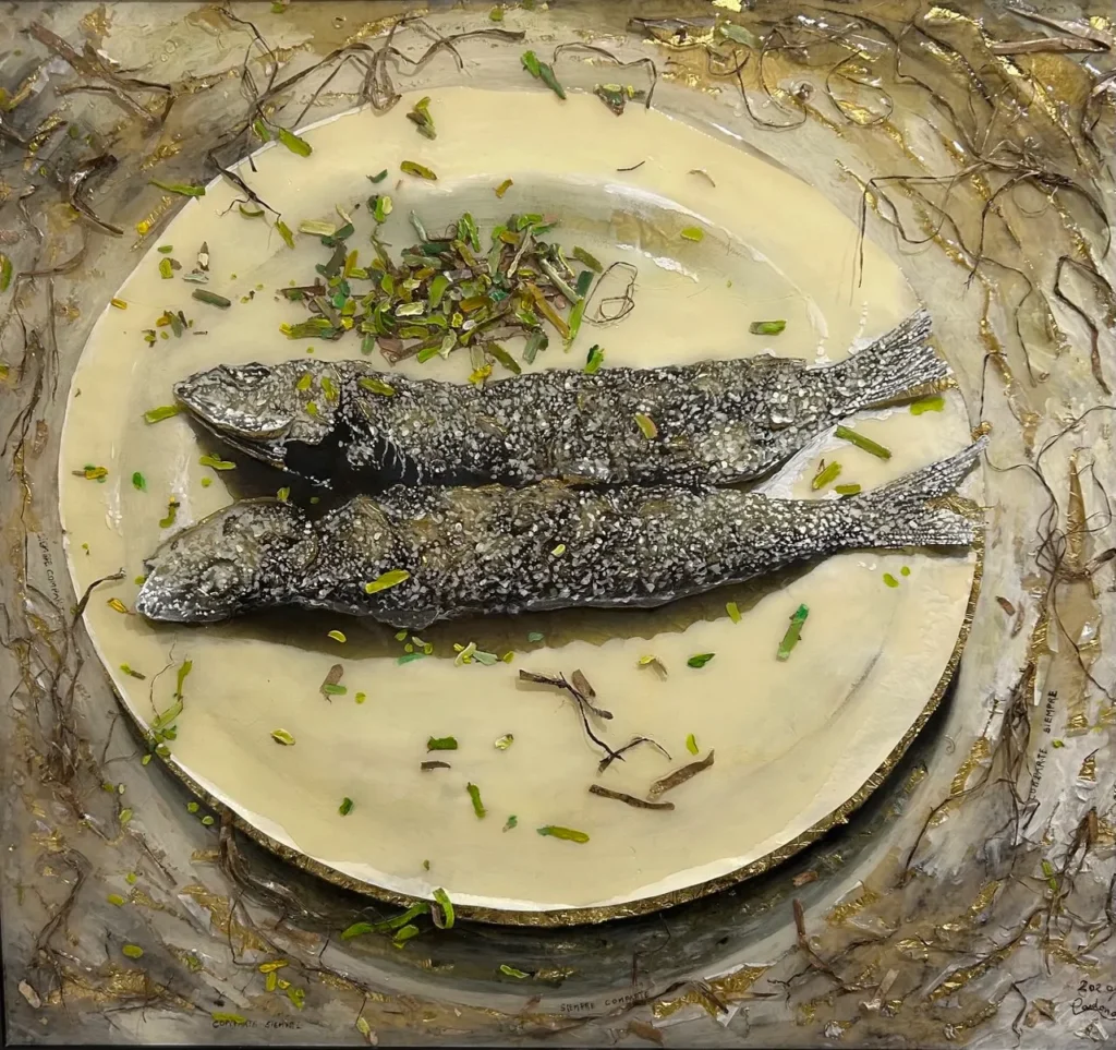 Dos peces cocinados con hierbas sobre plato artístico, rodeado de elementos naturales y acentos dorados