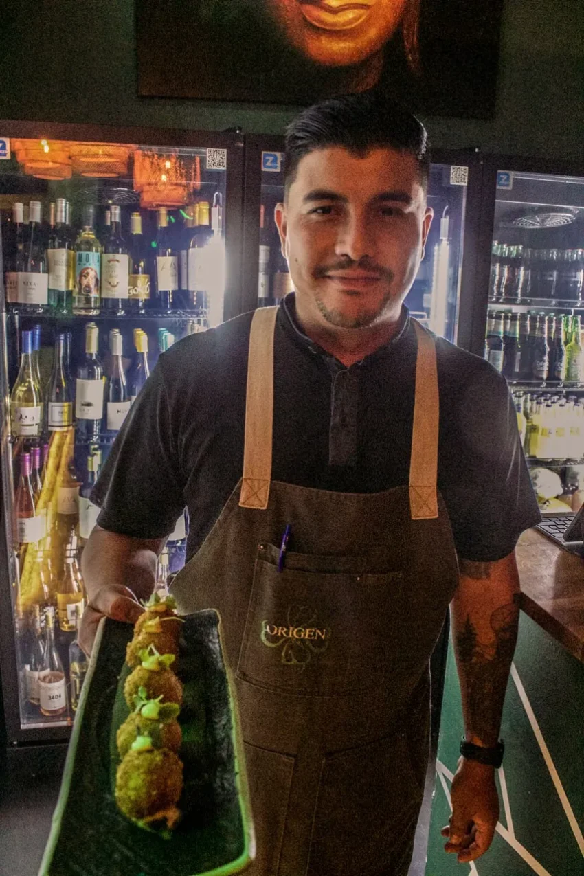 Jefe de sala de Origen presentando plato gourmet frente a vinoteca – Palma