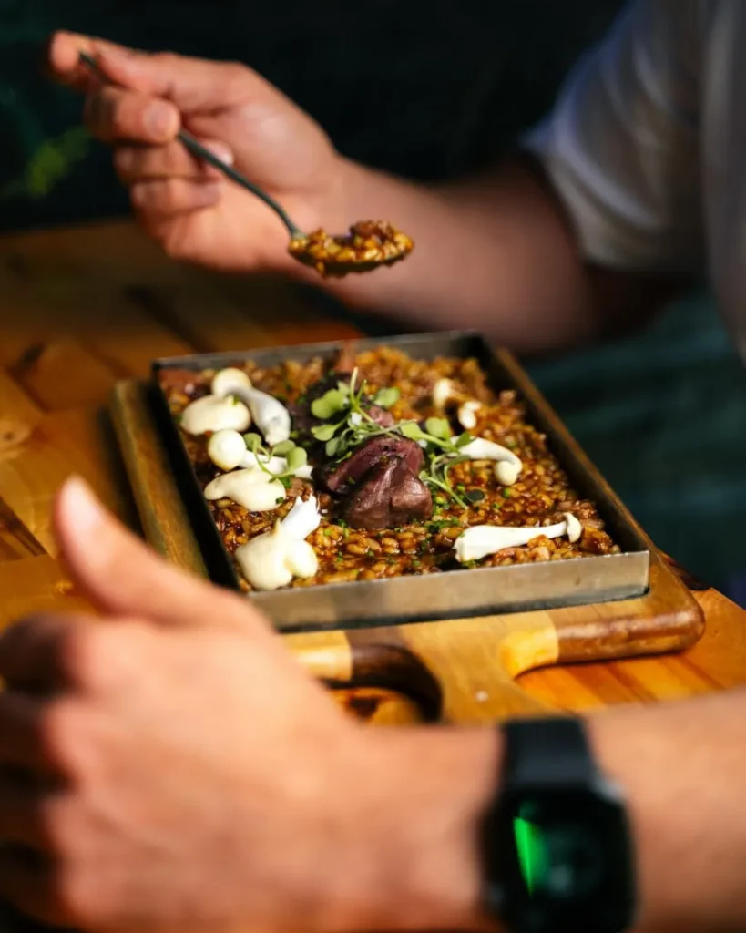 Comensal degustando plato gourmet de lentejas y carne con microgreens – Origen Palma