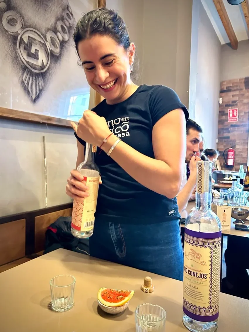 Cecilia propietaria del Xolotl sirviendo mezcal artesanal 400 Conejos en Acros Café Bar con copa y pomelo especiado