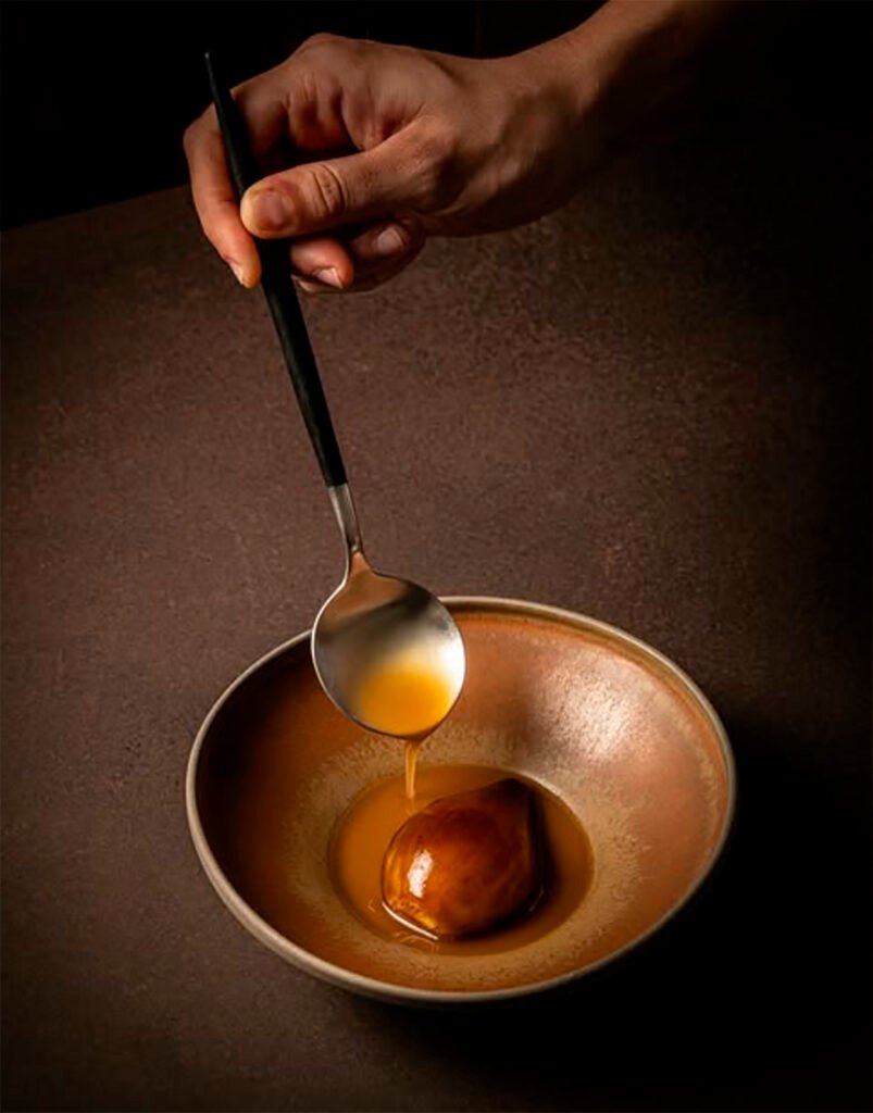 Un cuenco color tierra con cebolla glaseada en su jugo, y caldo de puchero.