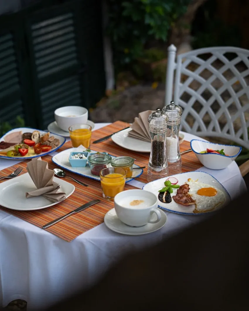 Desayuno al aire libre en Son Sant Jordi, con mesa elegantemente servida entre vegetación mediterránea.