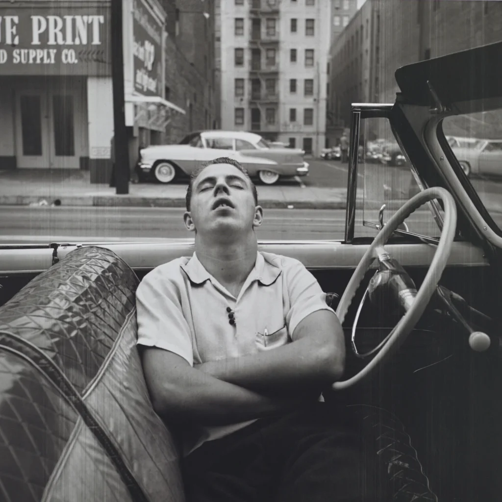 Fotografía de Vivian Maier: hombre dormido en un coche descapotable en plena ciudad