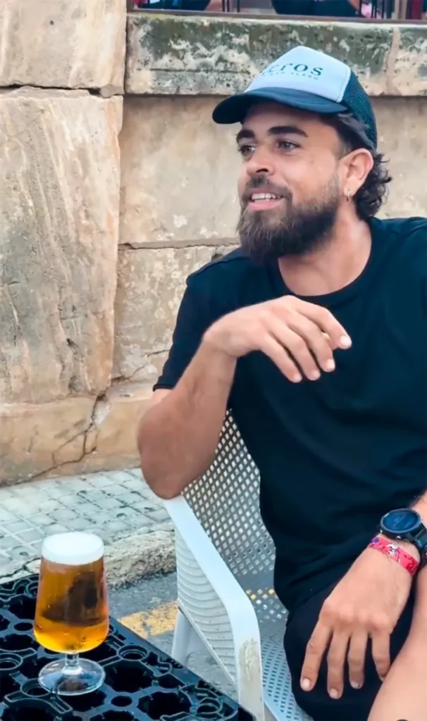 Joan ·Chochín" con gorra "Acros" disfrutando una cerveza en terraza al aire libre