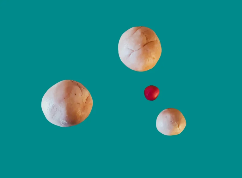 Cuatro esferas sobre fondo verde azulado, tres beige y una roja