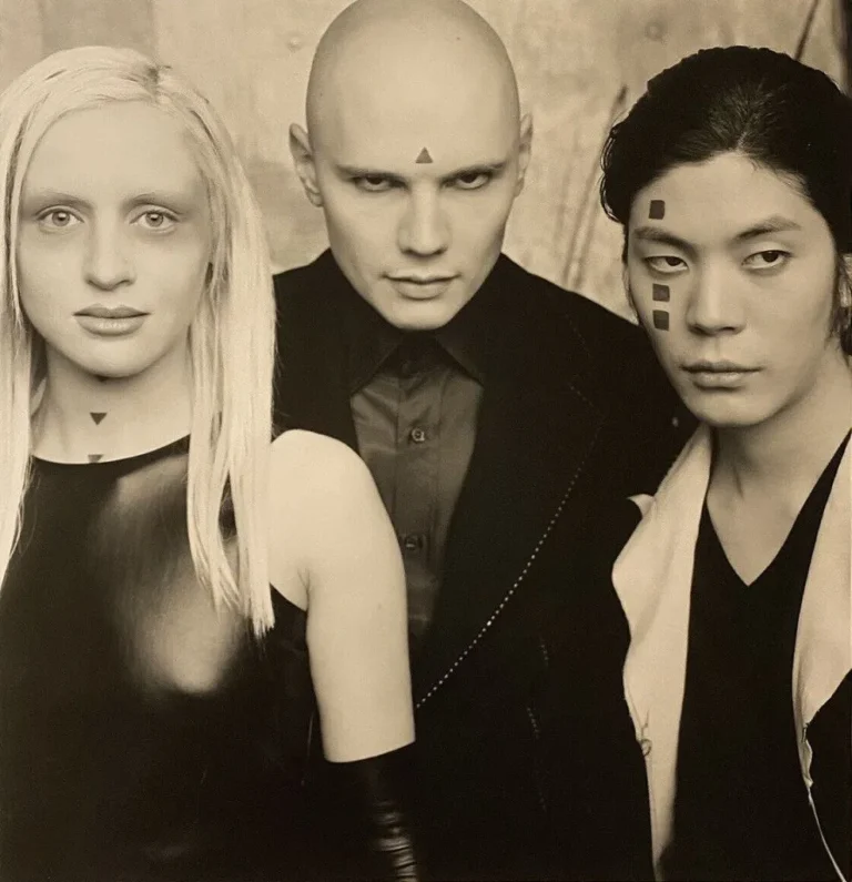 Retrato artístico en blanco y negro de Billy Corgan, James Iha y D’Arcy Wretzky con símbolos geométricos en el rostro, evocando la estética introspectiva del álbum Adore.