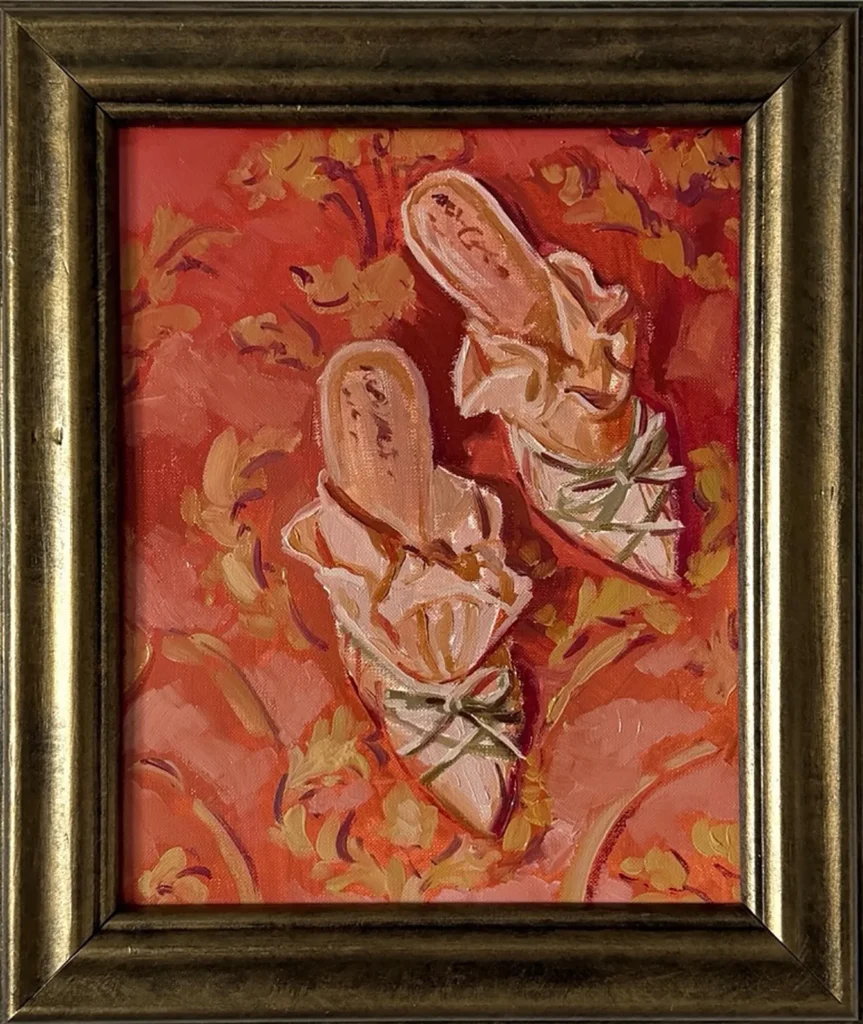 Zapatos de tacón claros con lazos y cintas verdes sobre fondo ornamental rojo