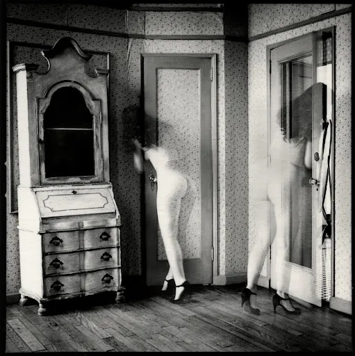 Figura femenina duplicada en movimiento frente a puertas, fotografía surrealista en blanco y negro