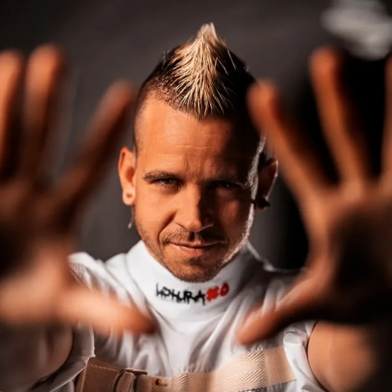 Dabiz Muñoz con mohawk y chaqueta blanca tipo camisa de fuerza, en pose frontal sobre fondo oscuro