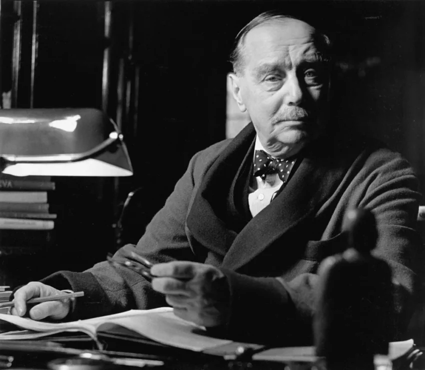 Retrato en blanco y negro de H. G. Wells sentado en escritorio con gafas y papeles