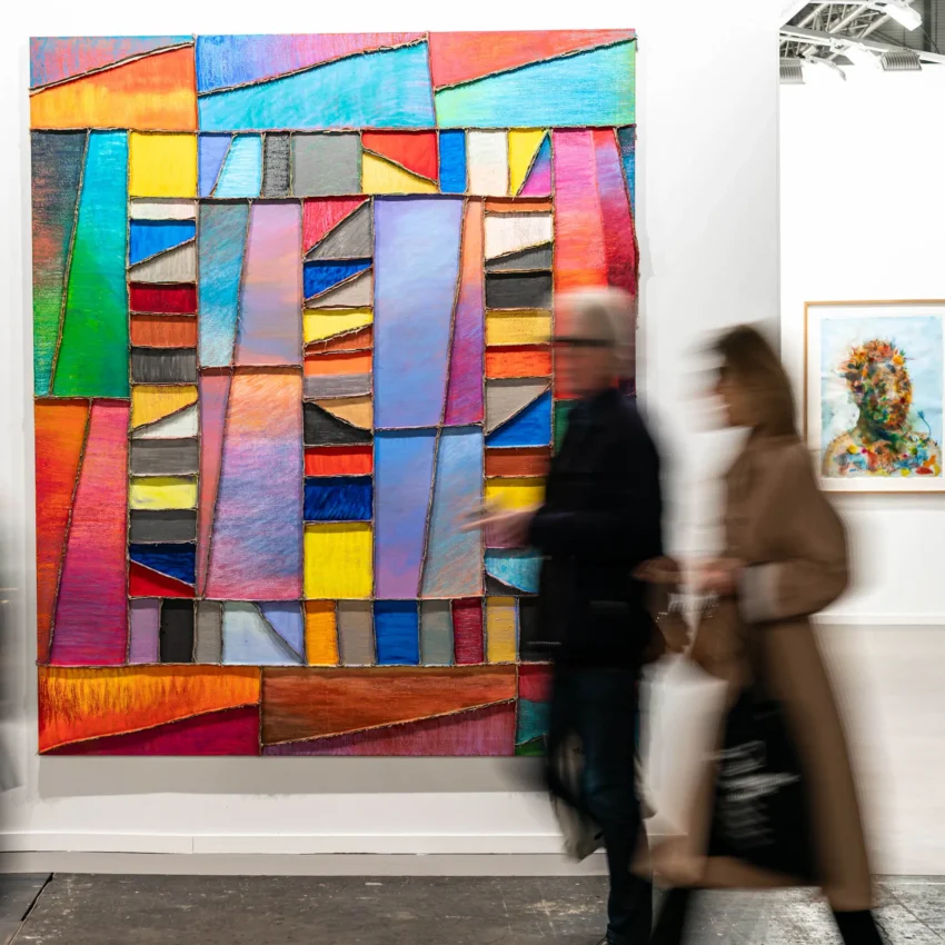 Visitantes en movimiento frente a obras de arte contemporáneo: una pintura abstracta vibrante y un retrato orgánico.