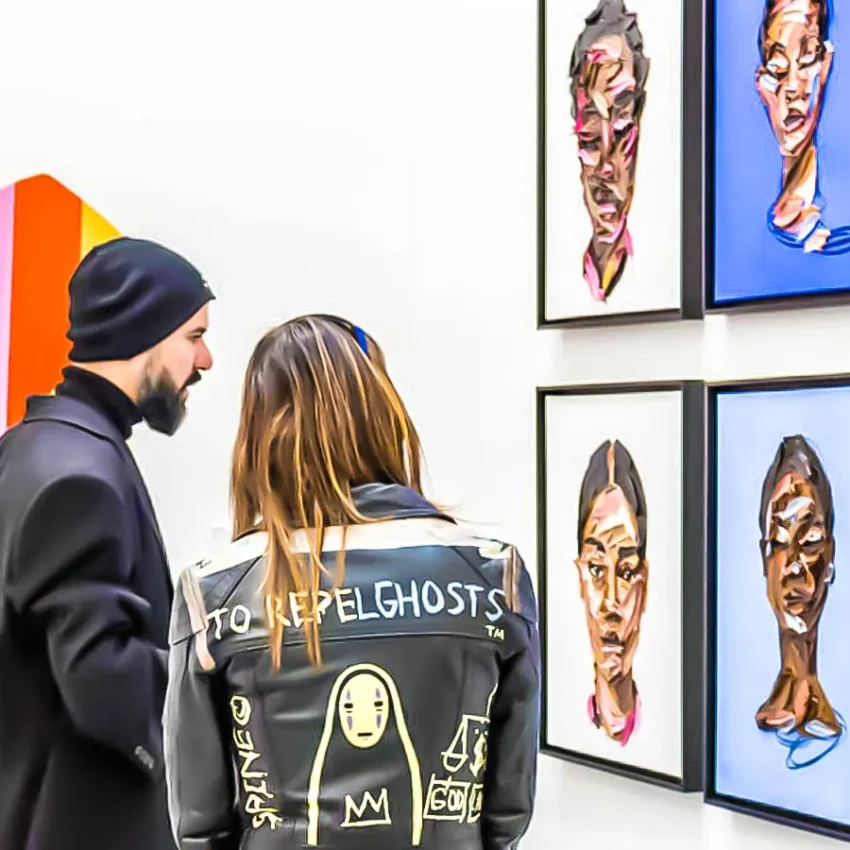 Dos visitantes observan retratos contemporáneos en una galería de arte en Madrid