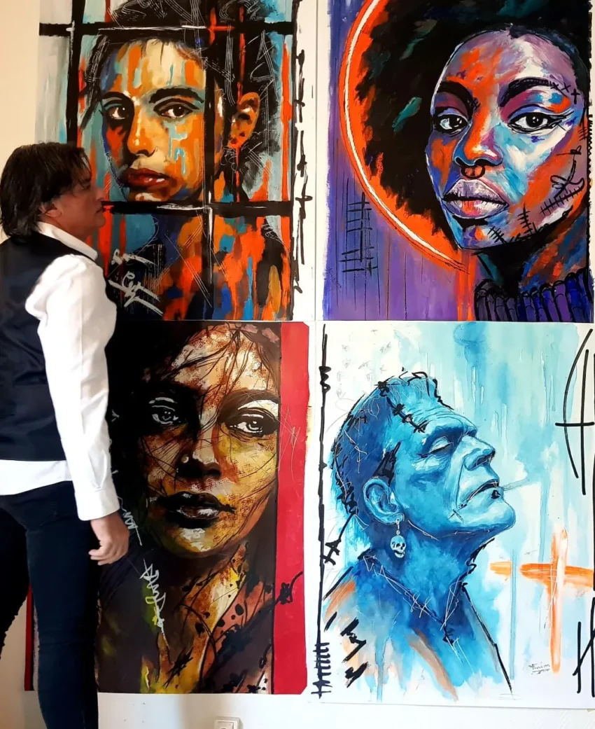 Retratos expresivos y coloridos de Franck Sastre junto al artista, en una instalación pictórica.