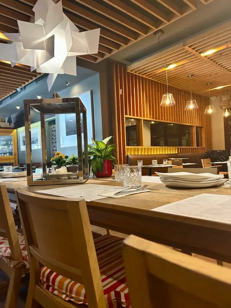 Mesa de madera elegantemente dispuesta en el restaurante S’Àngel de Palma, con luz cálida y detalles decorativos.