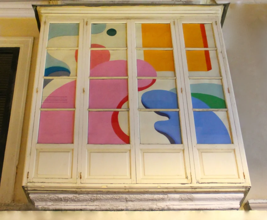 Ventanal urbano intervenido por Llorenç Garrit con formas orgánicas y colores vibrantes que crean una composición abstracta y dinámica.