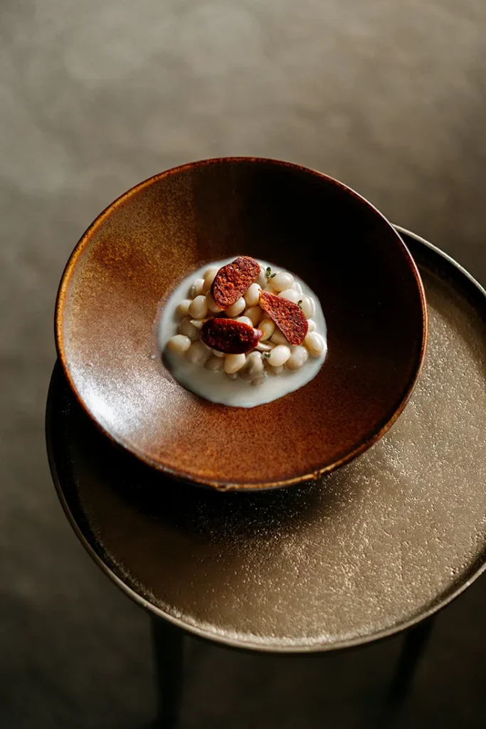 El neerlandés Bas van Kranen se ha convertido en una figura clave de la gastronomía contemporánea gracias a su concepto de "alta cocina consciente". En Flore**, fundado en 2021, van Kranen desarrolla una cocina basada en la microestacionalidad holandesa, eliminando los ingredientes tradicionales de lujo en favor de productos locales y sostenibles.