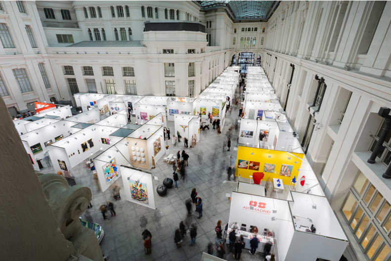 Vista general de Art Madrid con stands, visitantes y obras expuestas en la Galería de Cristal del Palacio de Cibeles.
