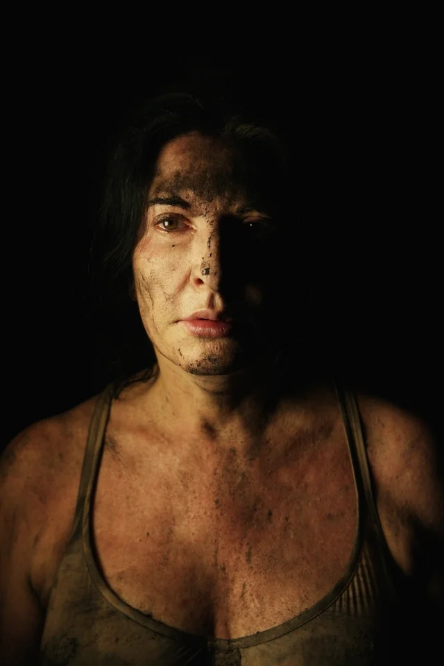 “Retrato dramático de Marina Abramovi? con rostro marcado y fondo oscuro.”