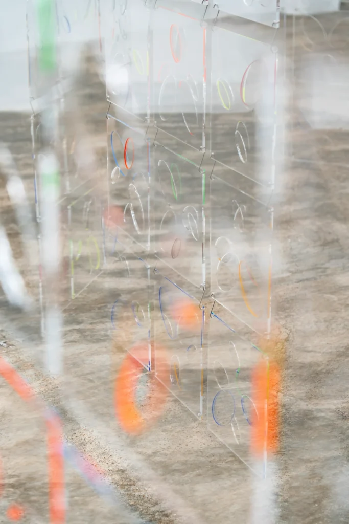 Detalle de paneles acrílicos de “Spinning Rumours Ópalo” de Carla Arocha y Stéphane Schraenen con círculos de colores y reflejos sobre el suelo.