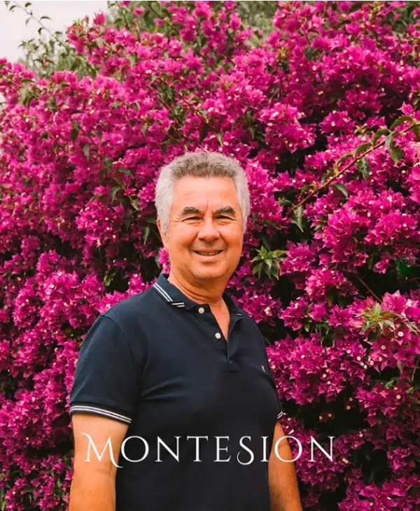 Carlos Feliu, enólogo de Montesión Wine Estate, posando frente a un arbusto en flor.