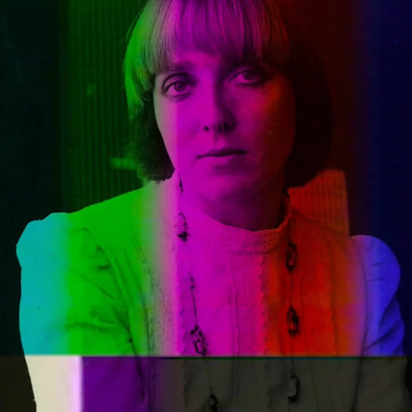 Retrato de Pola Weiss con el cabello corto y claro, vistiendo una blusa clara y un collar, sobre un fondo distorsionado con bandas de color tipo glitch.