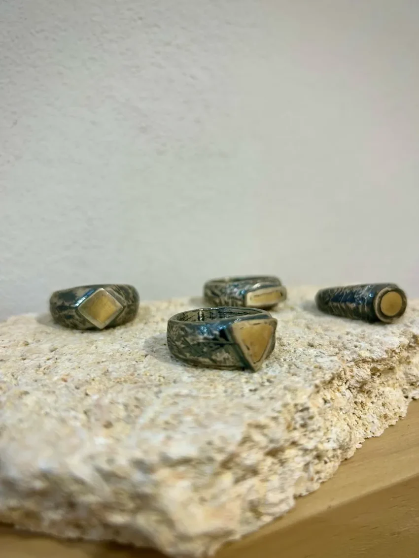 Anillos artesanales de Rako Joies con formas geométricas sobre una piedra texturizada.