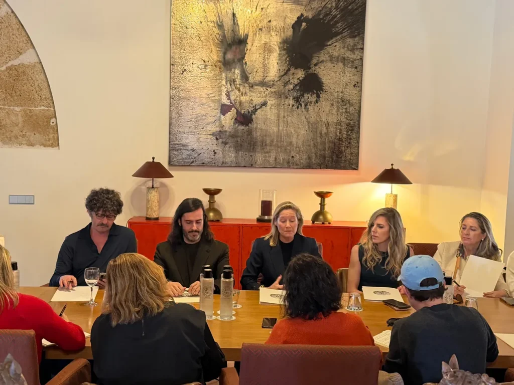 Grupo de personas reunidas alrededor de una mesa en una sala elegante, participando en una conversación durante un encuentro profesional.