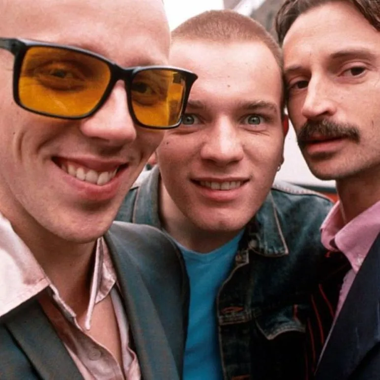 “Fotograma de Trainspotting con tres personajes posando juntos, estilo noventero y estética urbana.”