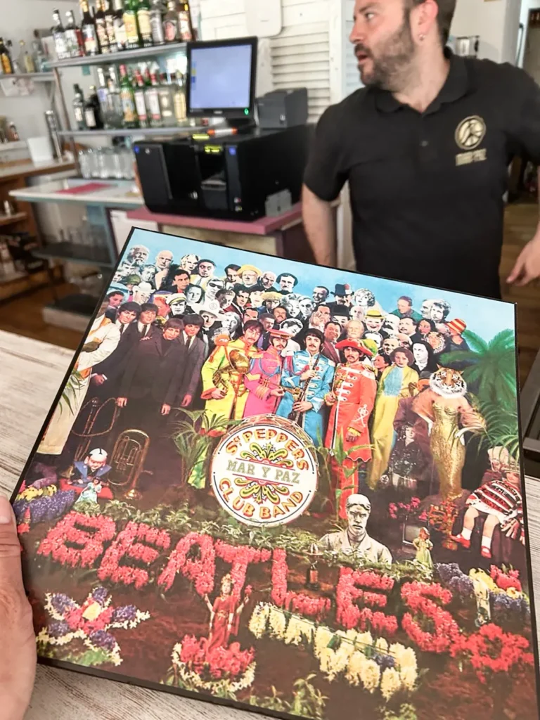 La carta-menú de mar y Paz, impacta visualmente por ser un vinilo y, cada uno con su propia carátula. En la imagen observamos la caratula de Sgt. Pepper’s Lonely Hearts Club Band (1967), de The Beatles, un prodigio de collage con 57 fotografías y nueve figuras de cera de personajes admirados por la banda como Bob Dylan, Lewis Carroll, Edgar Allan Poe, Aleister Crowley o Marilyn Monroe… La obra fue creada por los artistas pop Peter Blake y Jann Haworth, inspirados en un dibujo a tinta de Paul McCartney.