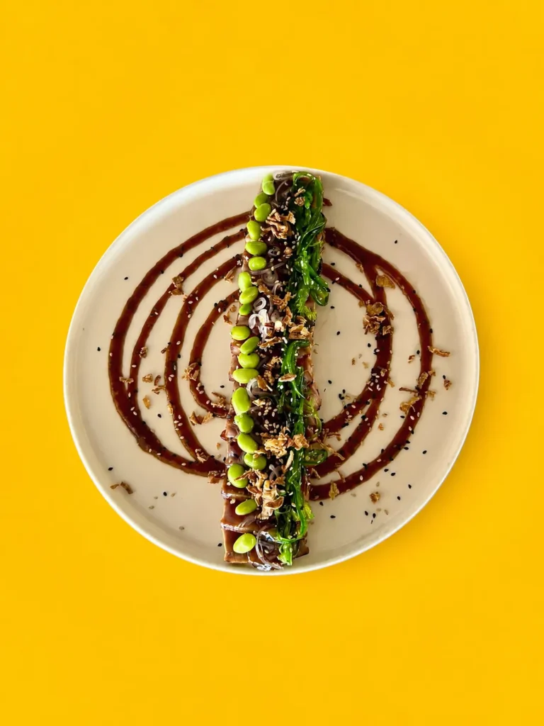 Tataki de atún en soja reposaba sobre algas, adornado con sésamo y edamame, como un pequeño paisaje marino.