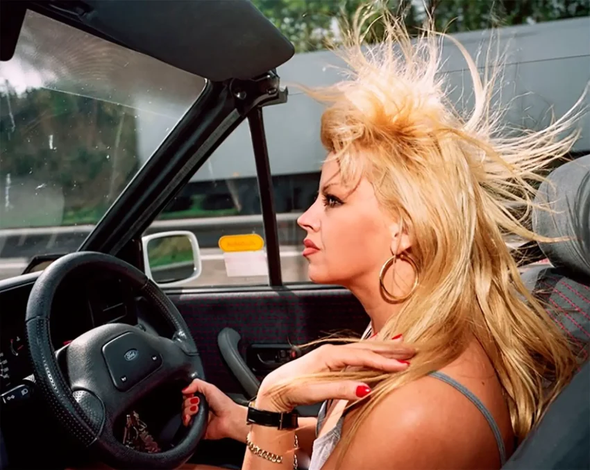Fotografía de la exposición A matter of taste de Martin Parr: una chica rubia conduciendo